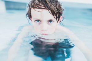 child staring doubtfully from a swimming pool